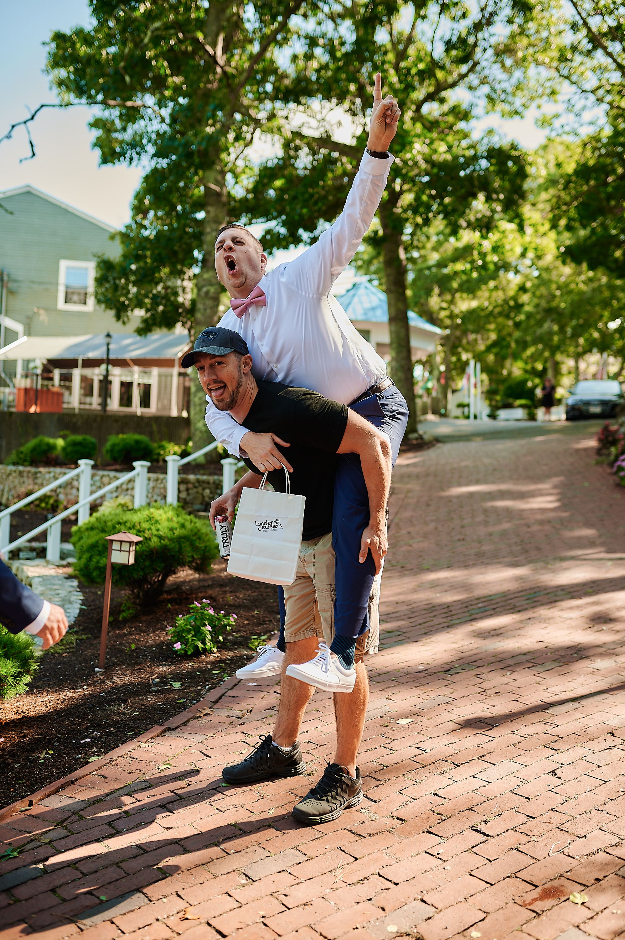 Candid wedding party photo of the groom being lifted by friends